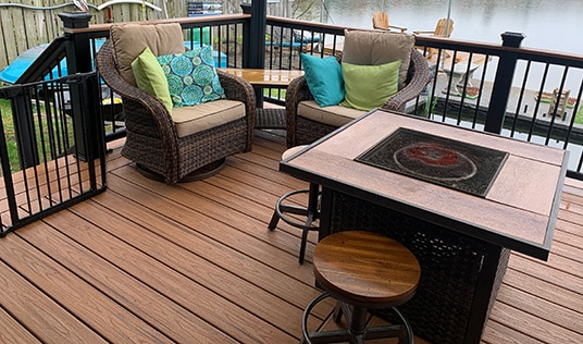 Custom Deck | Medium tone dark wood deck with dark railings and furniture | Backyard Creations | Custom Decks, Porches, and Pergolas