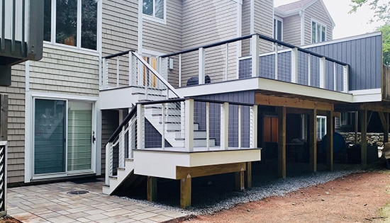 Custom deck with stairs | White stairs leading up to raised deck to tan house | Backyard Creations | Custom Decks, Porches, and Pergolas